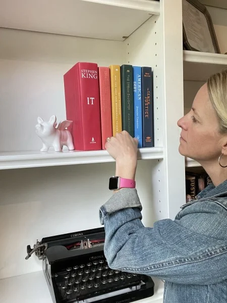 Wendy Sauer organizing books by color on a shelf